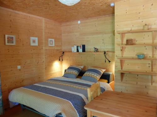 ein Schlafzimmer mit einem Bett in einem Zimmer mit Holzwänden in der Unterkunft Gite et cabane écologiques 1000 Pailles in Labastide-de-Virac