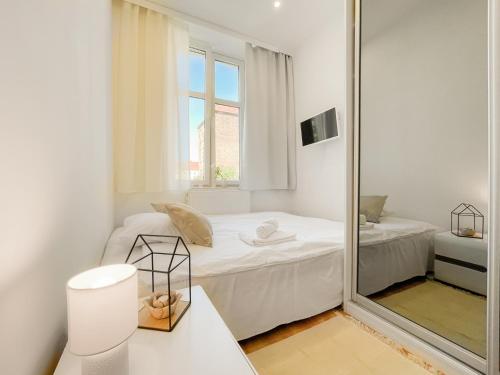Cette chambre blanche dispose d'un miroir et d'un lit. dans l'établissement COCO Apartments Gdańsk Centrum Górka, à Gdańsk