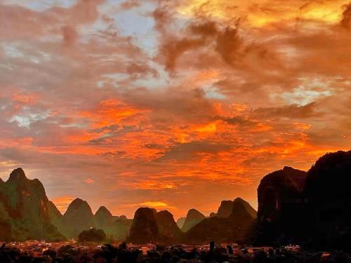 un tableau représentant un coucher de soleil avec des montagnes en arrière-plan dans l'établissement Riverside Retreat Hotel, à Yangshuo