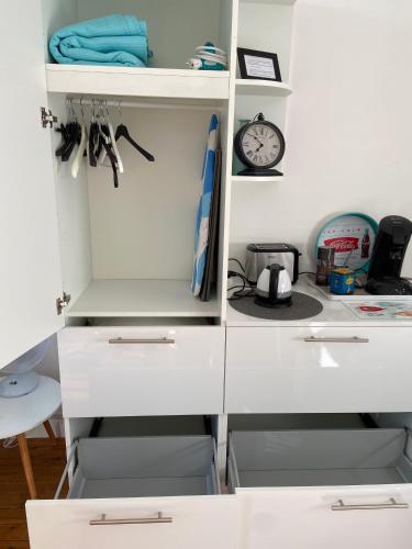 a closet with white cabinets and a clock on the wall at Studio (Coup de Coeur) Wimereux in Wimereux