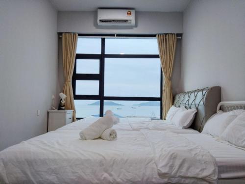 een knuffelbeer op een bed met een raam bij JESSELTON QUAY SEA VIEW in Kota Kinabalu