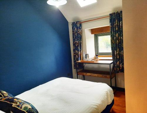 a bedroom with a blue wall with a bed and a desk at Longstone Bed & Breakfast in Challacombe