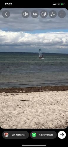 a picture of a person on the ocean with a sail in the water at Beachhouse Langeland 20 m to private Beach in Tranekær
