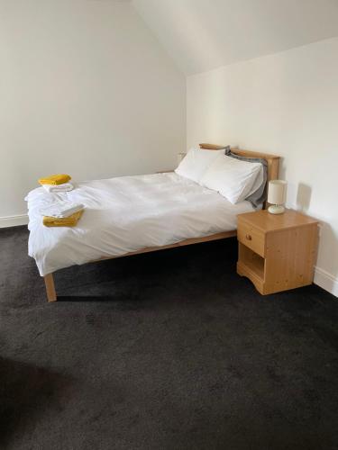 - une chambre avec un lit doté de draps blancs et d'une table de nuit dans l'établissement Newsagents Flat, à Lairg