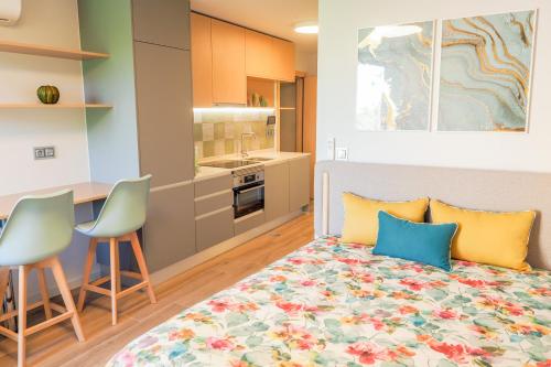 a bedroom with a bed and two chairs and a kitchen at RIACENTRUM - Smart Residence in Aveiro