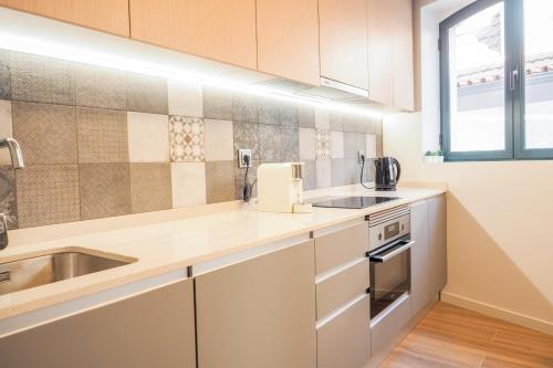 a kitchen with white cabinets and a sink at RIACENTRUM - Smart Residence in Aveiro