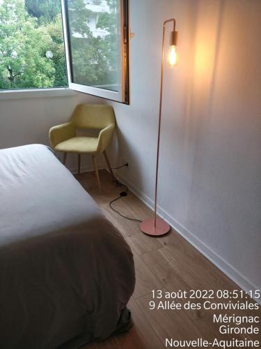 a bedroom with a bed and a lamp and a chair at Direct Aéroport et centre historique de Bordeaux in Mérignac
