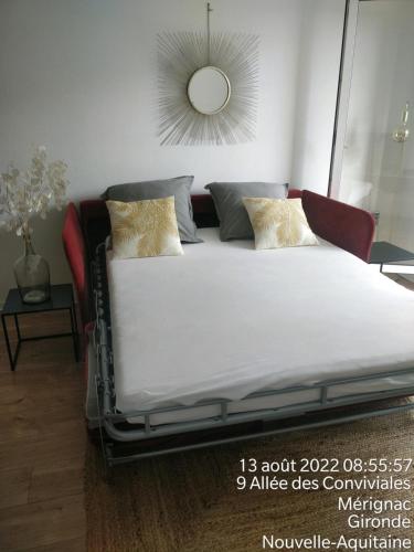 a bed with white sheets and pillows in a room at Direct Aéroport et centre historique de Bordeaux in Mérignac