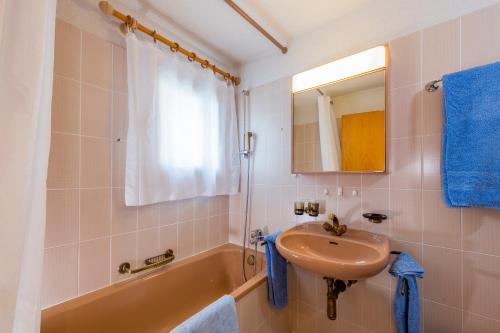 a bathroom with a sink and a tub and a mirror at Pra d'Sura 115 in Maloja