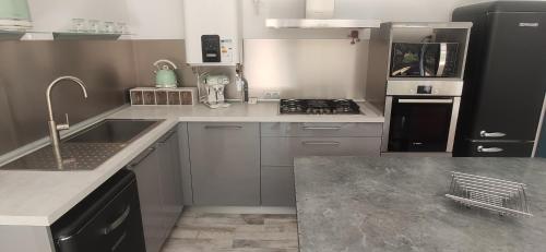 une cuisine avec un évier et une cuisinière dans l'établissement Rose BB maison de charme, aux Lecques