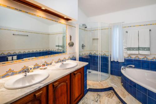 a blue tiled bathroom with two sinks and a tub at Casa Cupula in Poço Partido