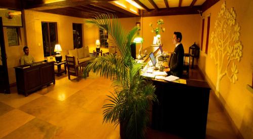 a man standing at a counter in a hotel lobby at Temple Tree Resort & Spa, Pokhara in Pokhara