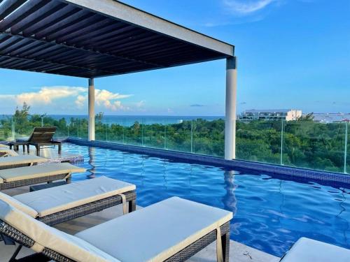 una piscina con sillas y vistas al océano en Terrazas by Andiani Travel, en Playa del Carmen