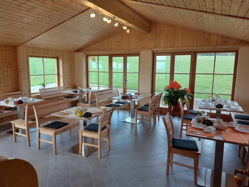 ein Esszimmer mit Tischen, Stühlen und Fenstern in der Unterkunft Gästehaus Annemarie in Rimsting