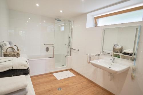 een witte badkamer met een douche en een wastafel bij Apartmán Casia in Jeseník