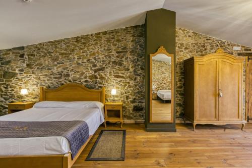 1 dormitorio con cama y pared de piedra en Mas Renart, en Mollet de Perelada
