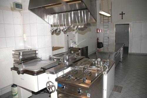 duża kuchnia ze sprzętem ze stali nierdzewnej i krzyżem w obiekcie Nikolauskloster w mieście Jüchen