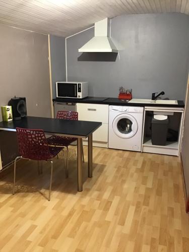 une cuisine avec une table et une machine à laver dans l'établissement Le Clau provençal, à Alès