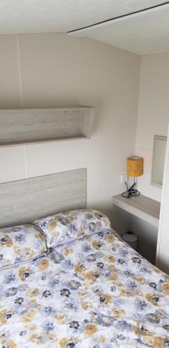 a bedroom with a bed with a floral bedspread at The selsey retreat in Selsey