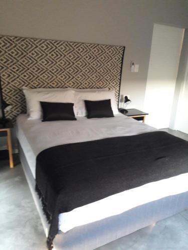 een slaapkamer met een groot bed met zwart-witte kussens bij Palahala in Marloth Park