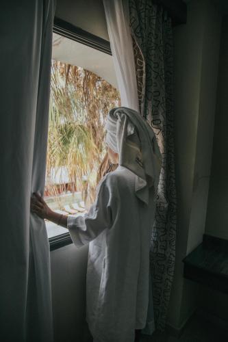 a woman wearing a mask looking out of a window at Hotel Puesta del Sol in San Rafael
