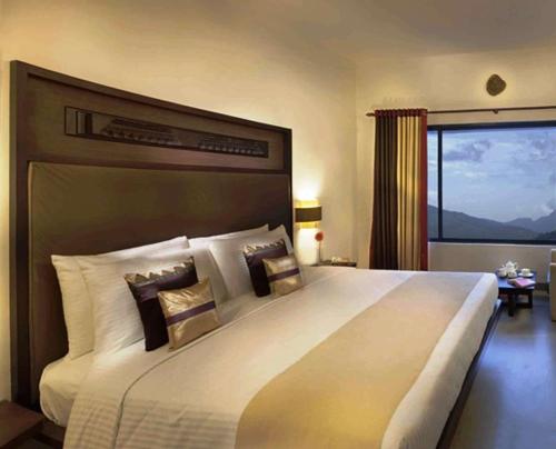 a bedroom with a large bed with a large window at Sterling Munnar in Munnar