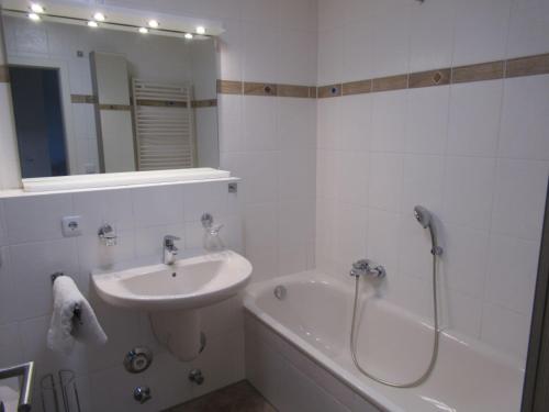 ein weißes Badezimmer mit einem Waschbecken, einer Badewanne und einer Dusche in der Unterkunft Auszeit am Fähranleger in Grünendeich