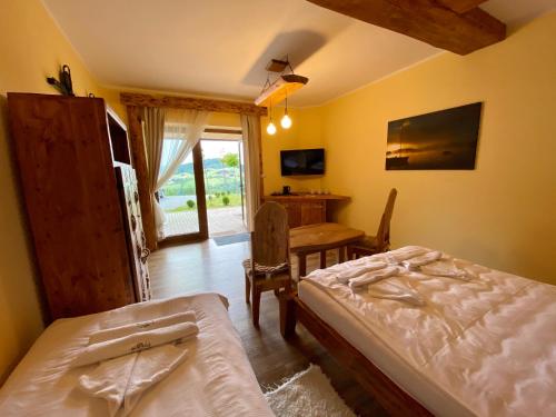 a bedroom with two beds and a table and a desk at Noclegi - Karczma Solina in Solina