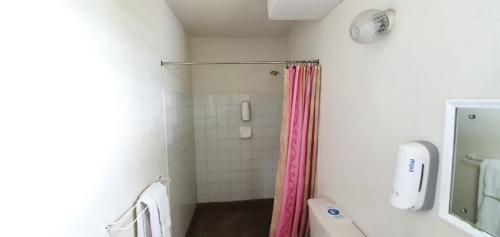 y baño con ducha y cortina de ducha rosa. en Malfranza Apartments, en Bridgetown