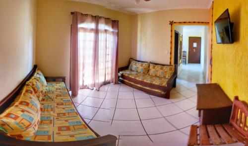 a living room with a couch and a tv in it at Peruíbe Suíte Flat Hotel in Peruíbe