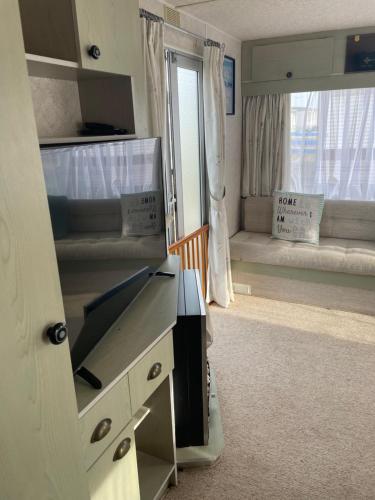 a room with a desk and a bedroom with a window at Hollie’s Hemsby holidays - static caravan in Hemsby