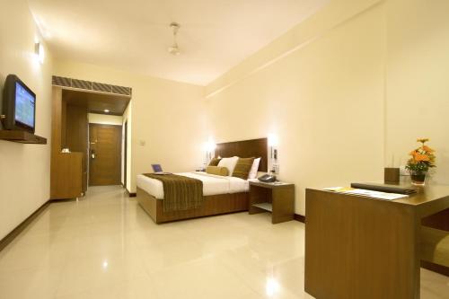 a bedroom with a bed and a desk and a television at Hotel Express Residency Vadodara in Vadodara
