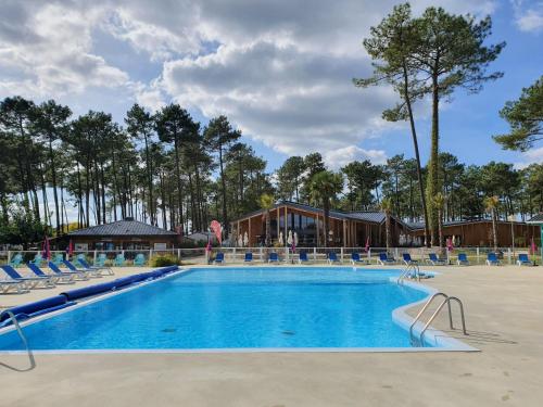 une piscine dans un complexe avec des chaises et un bâtiment dans l'établissement Bahiana, à Saint-Julien-en-Born