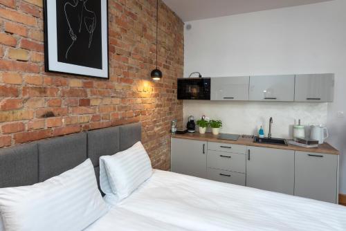 a bedroom with a white bed and a brick wall at PROVENIR HOME KWIATOWA 5 in Poznań