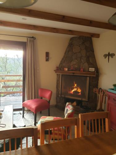 sala de estar con chimenea y silla roja en Terrazas de Piedra, en Santa Rosa de Calamuchita