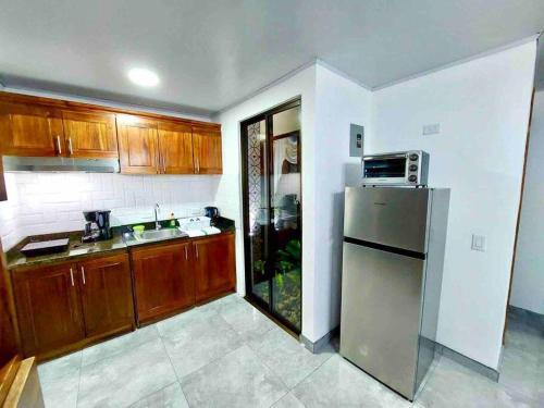 a kitchen with wooden cabinets and a stainless steel refrigerator at Airport SJO Residence - Edward & Familia Inn in Alajuela City