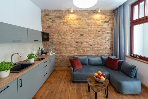 a living room with a blue couch and a brick wall at PROVENIR HOME KWIATOWA 5 in Poznań