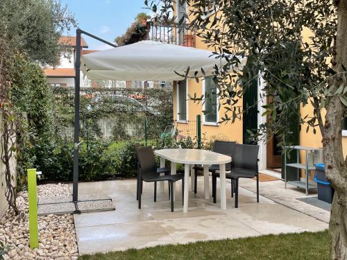 - une table et des chaises sous un parasol dans le jardin dans l'établissement APARTMENTS VALPOLICELLA: RESIDENZA OLIVO, à Fumane