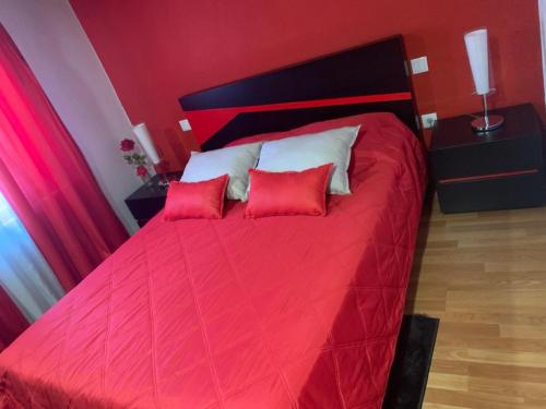1 dormitorio con 1 cama roja y 2 almohadas rojas en Casa da Gracita, en Pereira