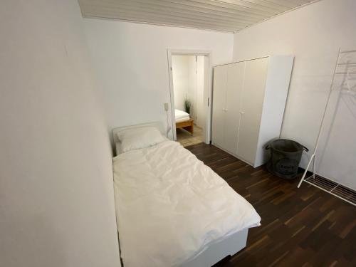 Kleines weißes Zimmer mit einem Bett und einem Schrank in der Unterkunft Ferienwohnung Geiger in Sersheim