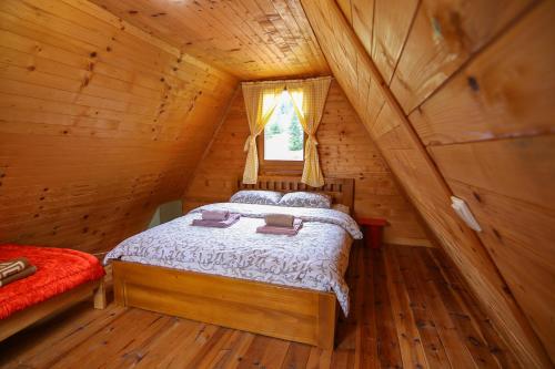 ein Schlafzimmer mit einem Bett in einem Blockhaus in der Unterkunft Lodge Drveni Kutak in Sekulić 