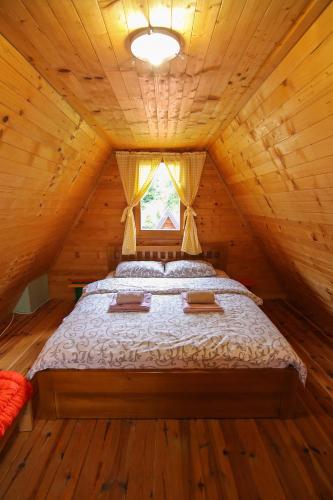 a bed in a wooden cabin with a window at Lodge Drveni Kutak in Sekulić 