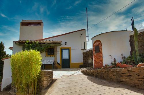 Biały dom z żółtymi drzwiami i kamienną ścianą w obiekcie Monte Alecrim w mieście Alandroal
