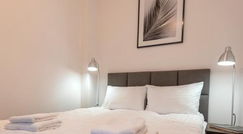 a bedroom with a bed with white sheets and two lights at PROVENIR HOME KWIATOWA 5 in Poznań