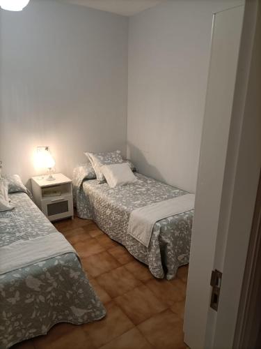a bedroom with two beds and a night stand with a lamp at Disan 3B in Portonovo