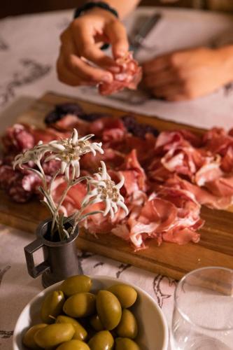a table with a cutting board of bacon and a plate of olives at Hotel Walser Courmayeur in Courmayeur