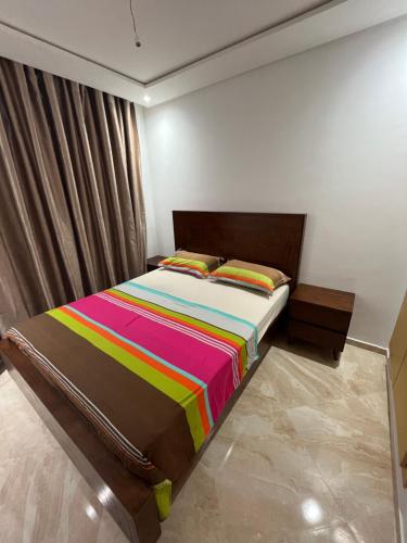 - une chambre avec un lit et une couverture colorée dans l'établissement sidi rahal ramoflores, à Sidi Rahal