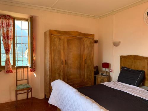 Pognana LarioにあるApartment Casa Dono Il lagoのベッドルーム1室(ベッド1台、キャビネット、窓付)