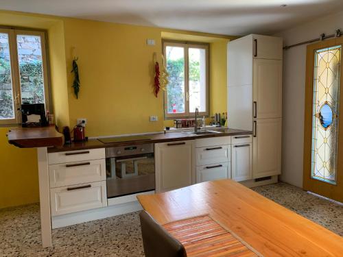 eine Küche mit gelben Wänden und einem Holztisch in der Unterkunft Apartment Casa Dono Il lago in Pognana Lario