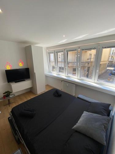 a large black bed in a room with windows at [Udine Centro] Ade Apartment in Udine